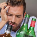 Homme-qui-a-la-gueule-de-bois-devant-des-bouteilles