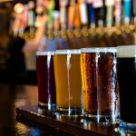 A flight of 4 craft beers lined up on the bar.