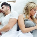 Upset couple lying back to back in bed